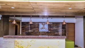 A reception area with a marble counter, three pendant lights, and a logo on the wall. - Retro Hotel and Spa (Kathmandu)