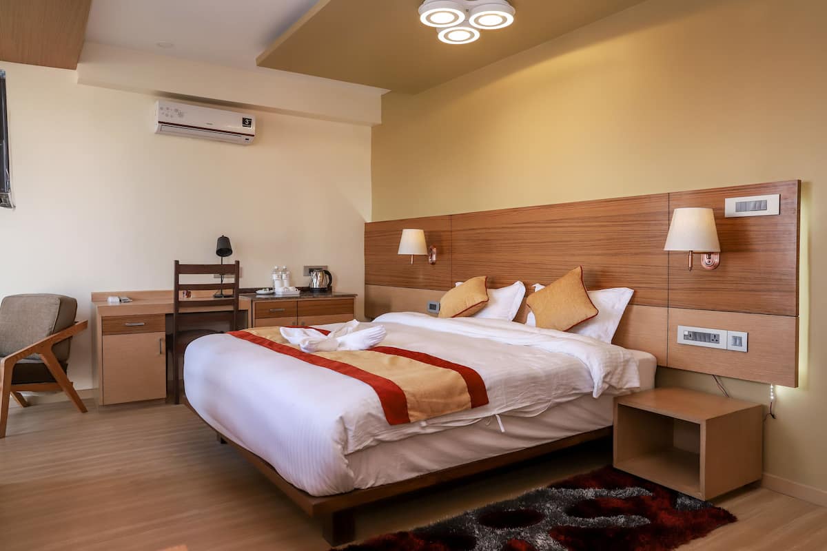 A hotel room with a wooden bed, bedside tables, a desk, and a chair.