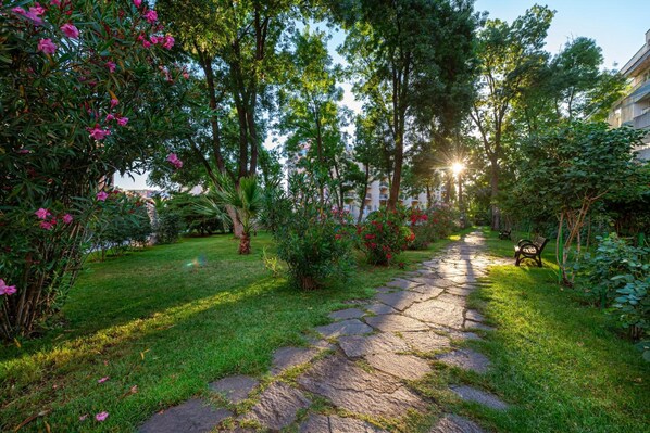 Un camino de piedra en un jardín con follaje y flores.