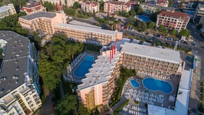 Un hotel con varias piscinas, una terraza en la azotea y un estacionamiento.