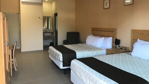 A hotel room with two beds, a desk, a chair, a mirror, and a bathroom visible through an open door. - Navola Inn (Culiacán)