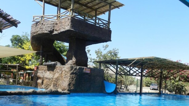 A pool with a rock structure and a slide. - Navola Inn (Culiacán)
