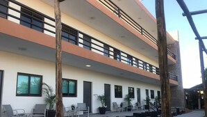A multi-story building with outdoor seating areas, potted plants, and a staircase leading to an upper level. - Navola Inn (Culiacán)