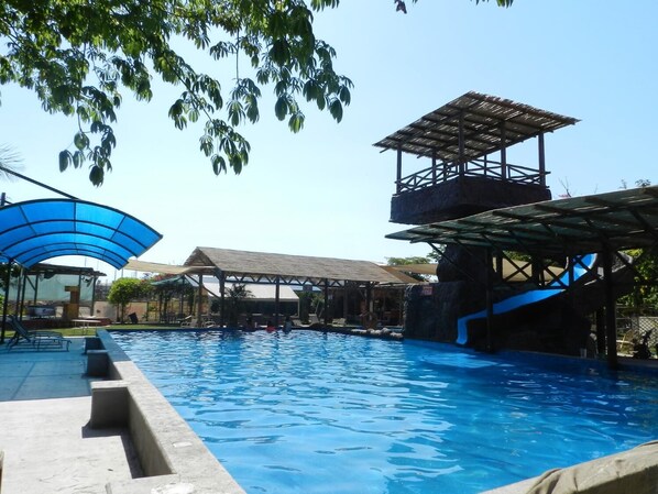 A swimming pool with a shaded area and a slide.