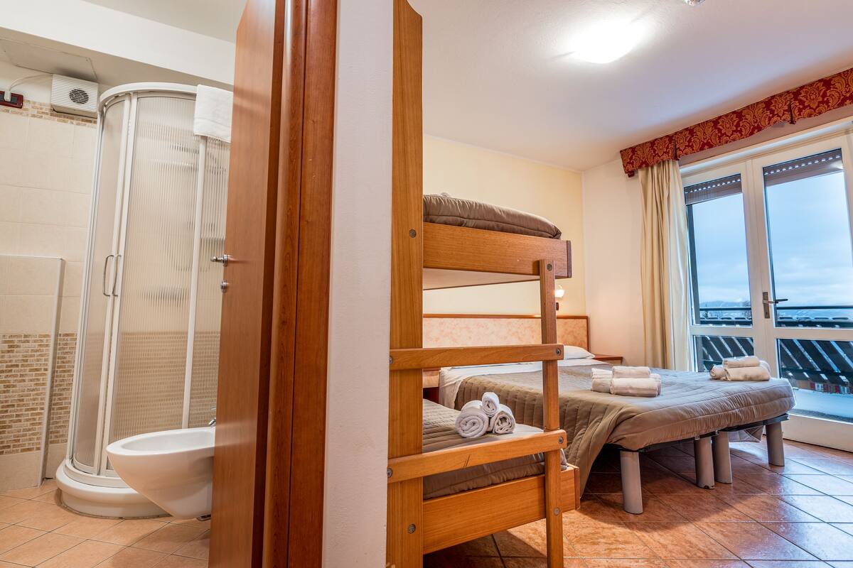A room with a bunk bed, a shower, and a toilet.