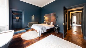 A bedroom with a bed, a radiator, a round white rug, and a wooden floor. - Linton Collection - Lord Lyons Chambers (Edinburgh)