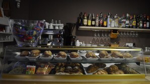 Vitrina de panadería con diversos productos horneados y una máquina de café.