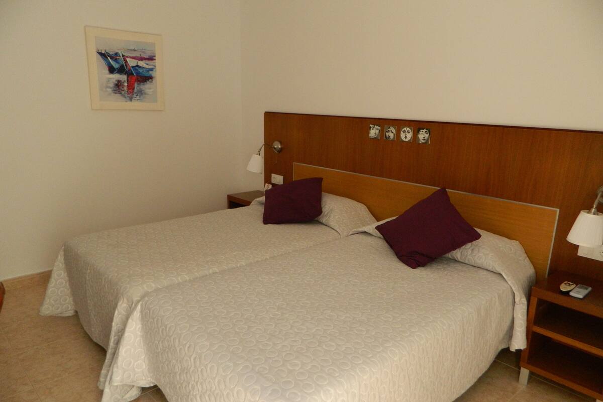 A double bed with a wooden headboard, two bedside tables, and a nightstand with a lamp.