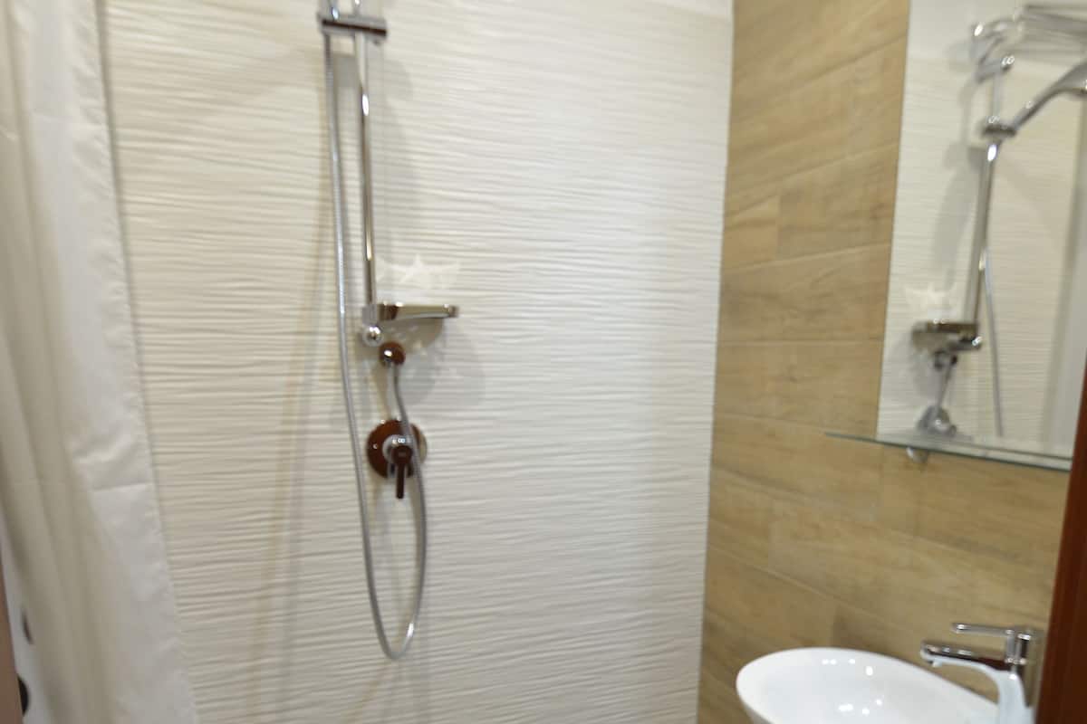 A bathroom with a shower, toilet, and sink.