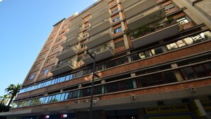 A multi-story building with balconies, large windows, and a ground-level storefront.