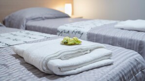 A hotel room with two beds, each with a white blanket and a pillow.