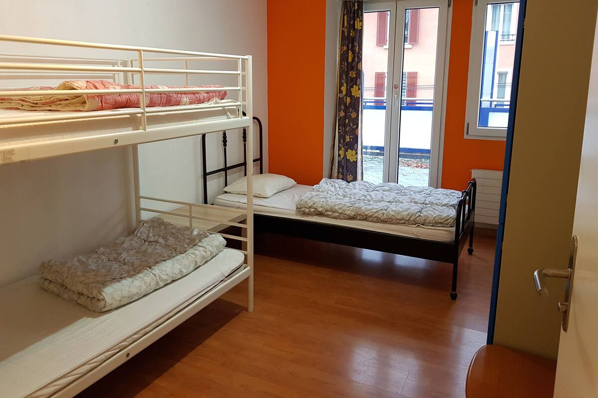 A bunk bed room with a window and a door.