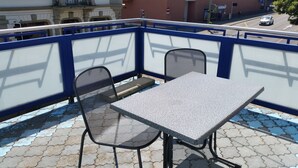 A balcony with a table and two chairs, a blue railing, and a view of the street below. - Bellpark Hostel (Kriens)