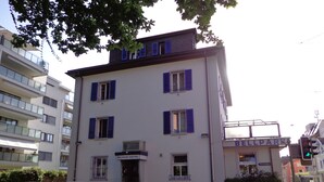 A two-story building with a sign reading "Bellpark Hostel." There are cars parked in front, and the building has multiple windows with shutters. - Bellpark Hostel (Kriens)