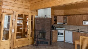 A wooden cabin interior with a kitchen, dining area, and a fireplace.