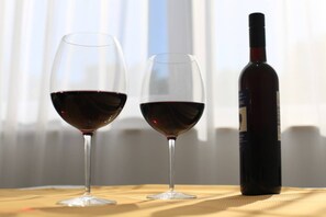 Zwei Weingläser und eine Flasche auf einem Tisch, im Hintergrund ein Fenster.