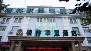 Een hotelgevel met een groot bord in Chinese karakters, een duidelijke ingang met glazen deuren, en een traditionele architectuur met zuilen.
