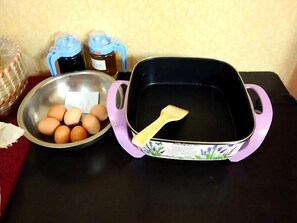 A kitchen counter with a bowl of eggs, a frying pan, and two jars of honey.