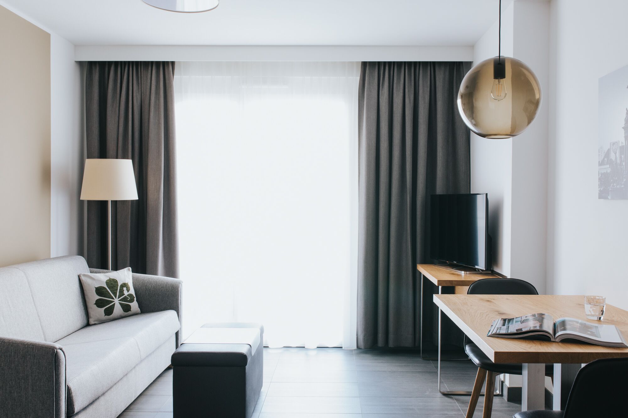 Una sala de estar moderna con sofá, mesa de centro, televisor y comedor con mesa y sillas.