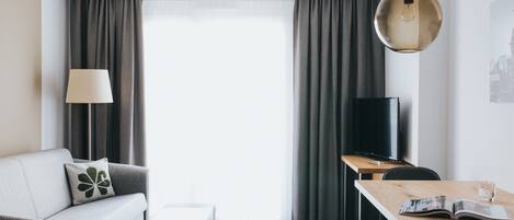 Una sala de estar moderna con sofá, mesa de centro, televisor y comedor con mesa y sillas.