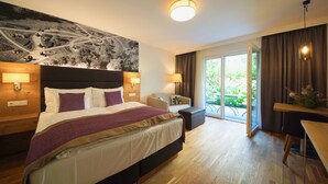 Quarto de hotel com cama grande, escrivaninha, cadeira, sofá e vista para o exterior.