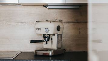 A kitchen with white cabinets, a coffee machine, and a wooden backsplash.