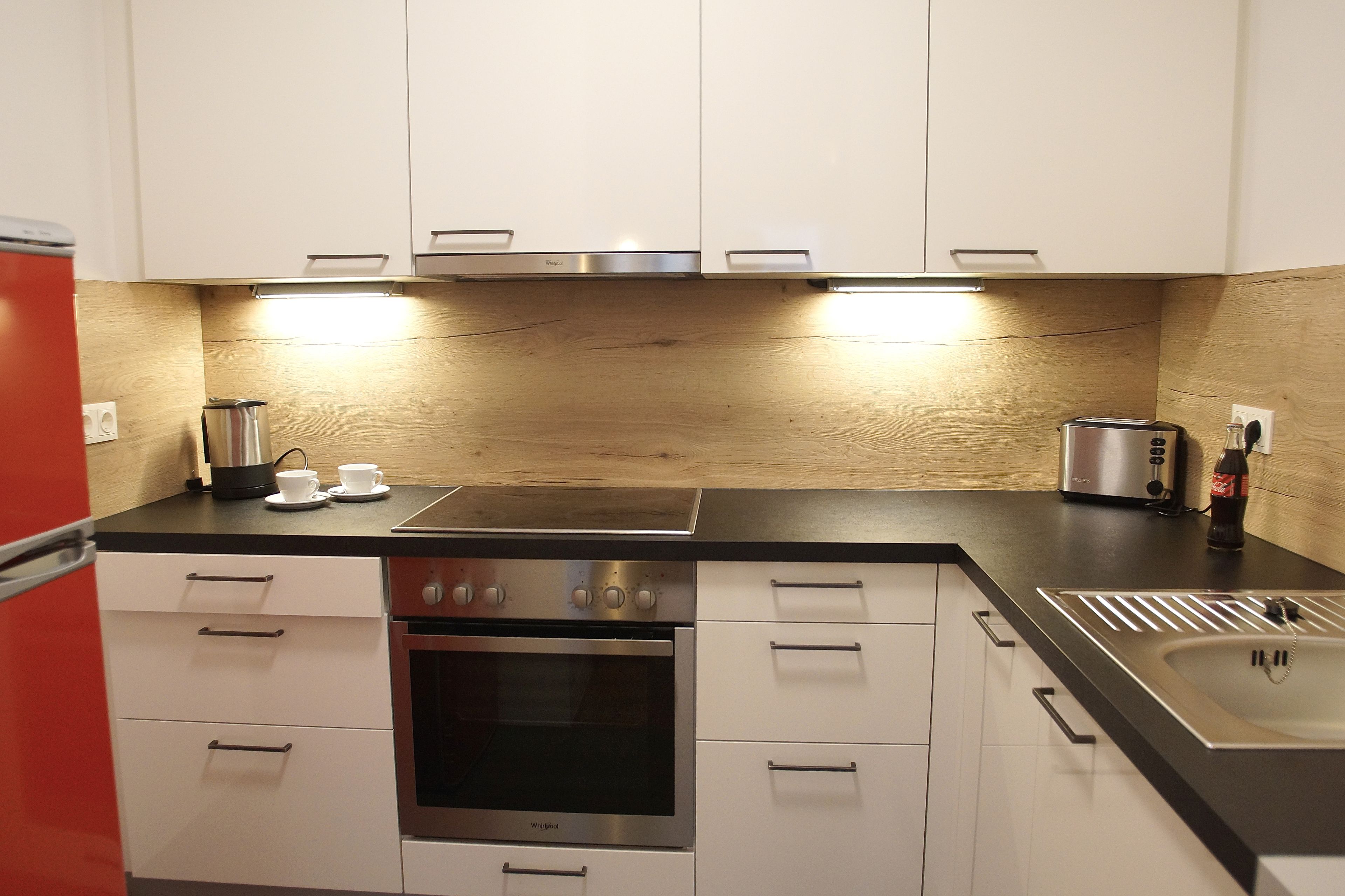 Eine moderne Küche mit weißen Schränken, einem Edelstahlbackofen, einer Spüle und einem Toaster.
