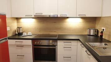 Eine moderne Küche mit weißen Schränken, einem Edelstahlbackofen, einer Spüle und einem Toaster.