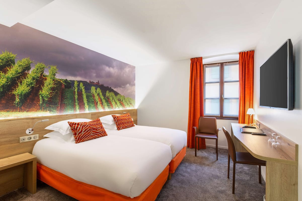 Una habitación de hotel con una cama grande, un escritorio, una silla y un televisor.