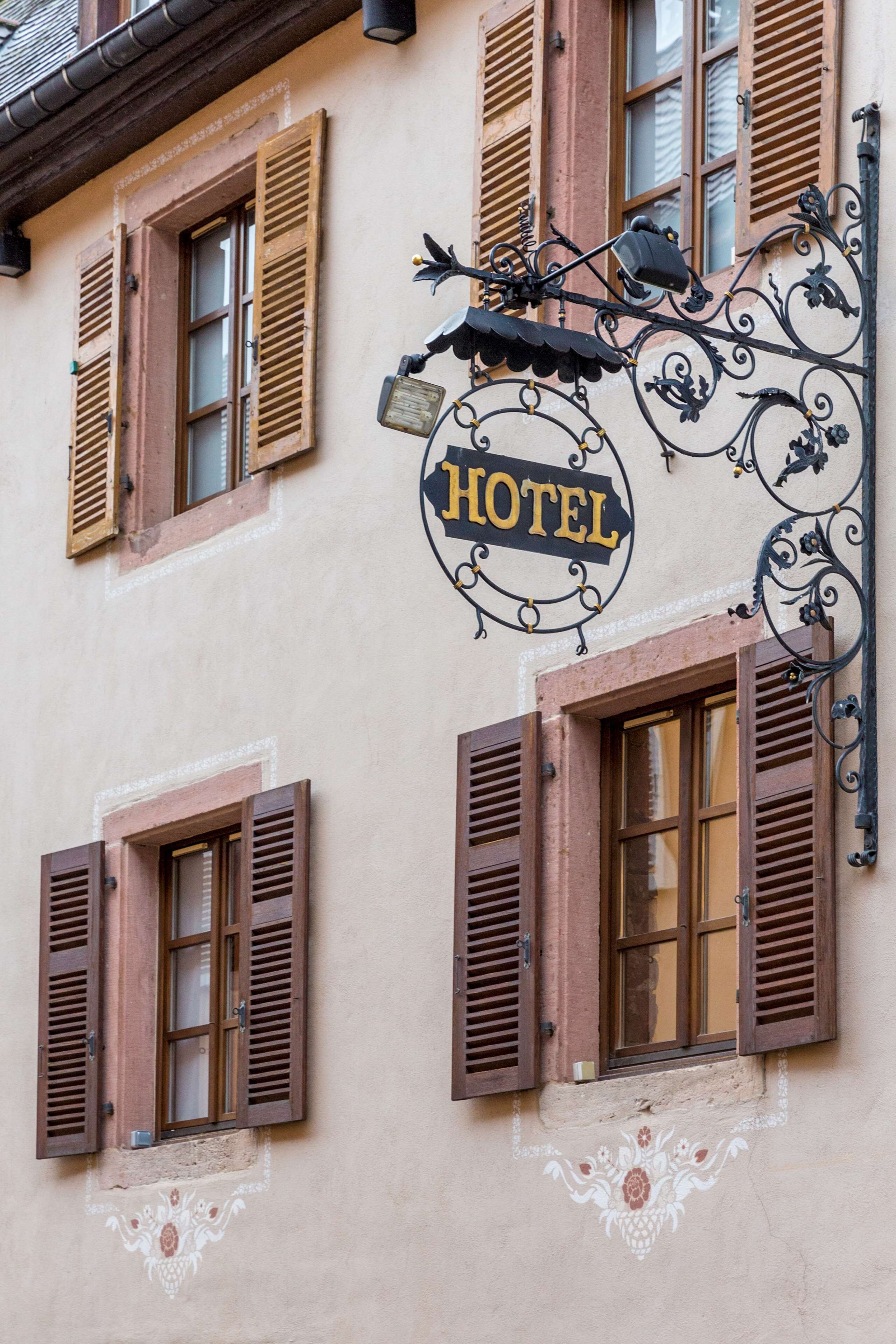 A building with a "HOTEL" sign, wooden shutters on windows, and a decorative awning.