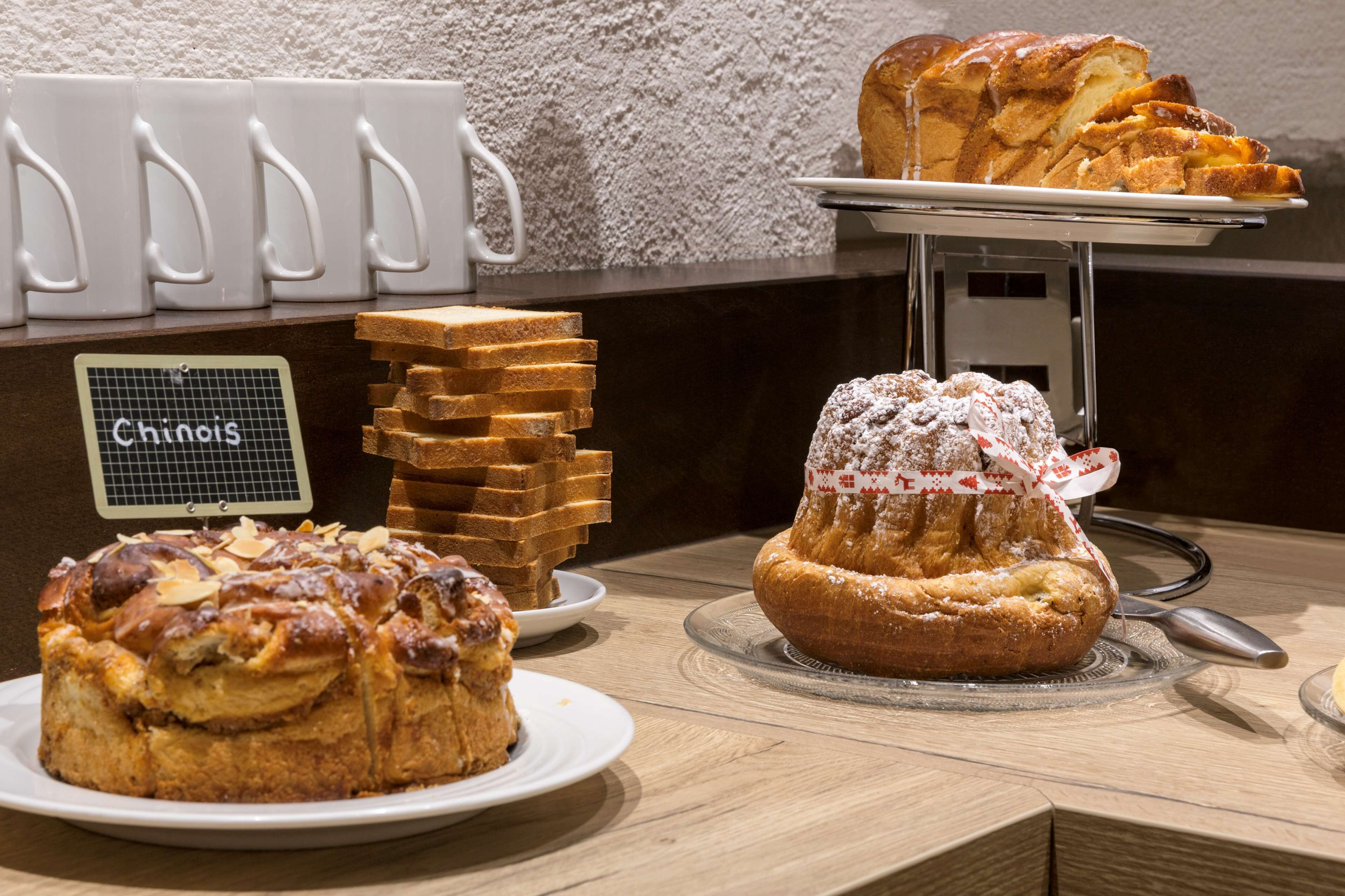 A display of various baked goods including a cake, bread, and pastries on a counter.