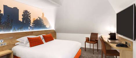 Habitación de hotel con cama, escritorio, silla y un televisor grande.