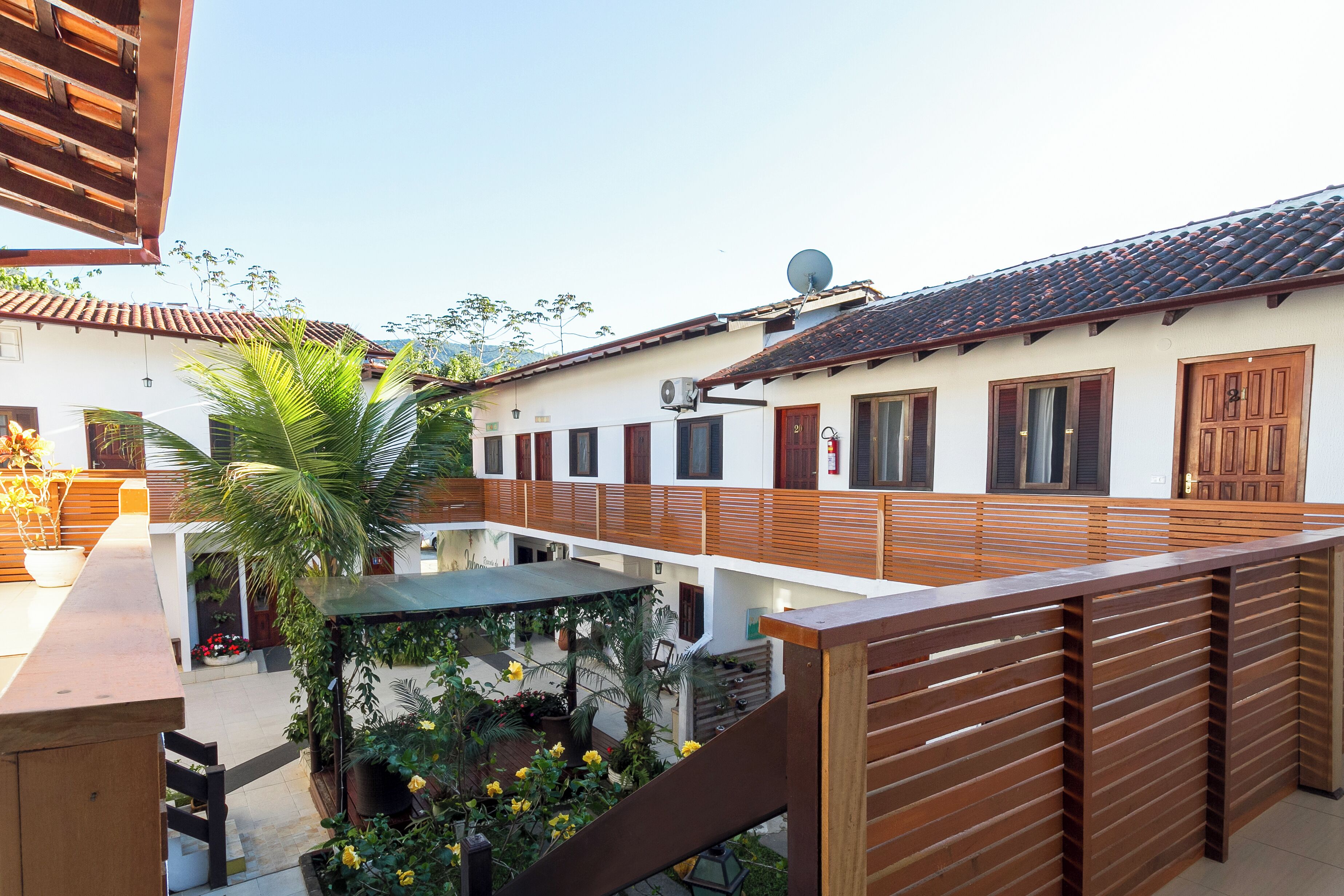 A courtyard with a wooden deck, potted plants, and a building with a tiled roof.