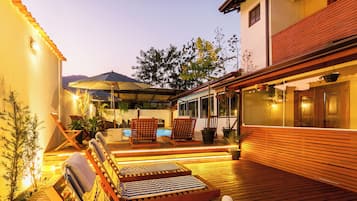 Een buitenzwembad, parasols bij het zwembad en ligstoelen