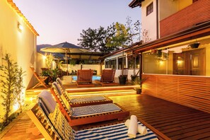 Una terraza de madera con sillones de descanso y zona de piscina.
