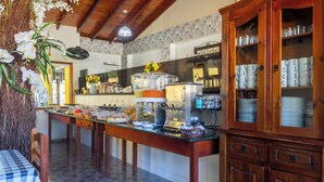 A kitchen with a buffet setup, including a coffee station, a refrigerator, and a cabinet with dishes. - Pousada Recanto do Jabaquara (Paraty)