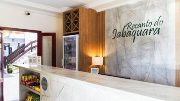 Un área de recepción con pared de mármol, un mueble de madera, un refrigerador y una lámpara de pared.
