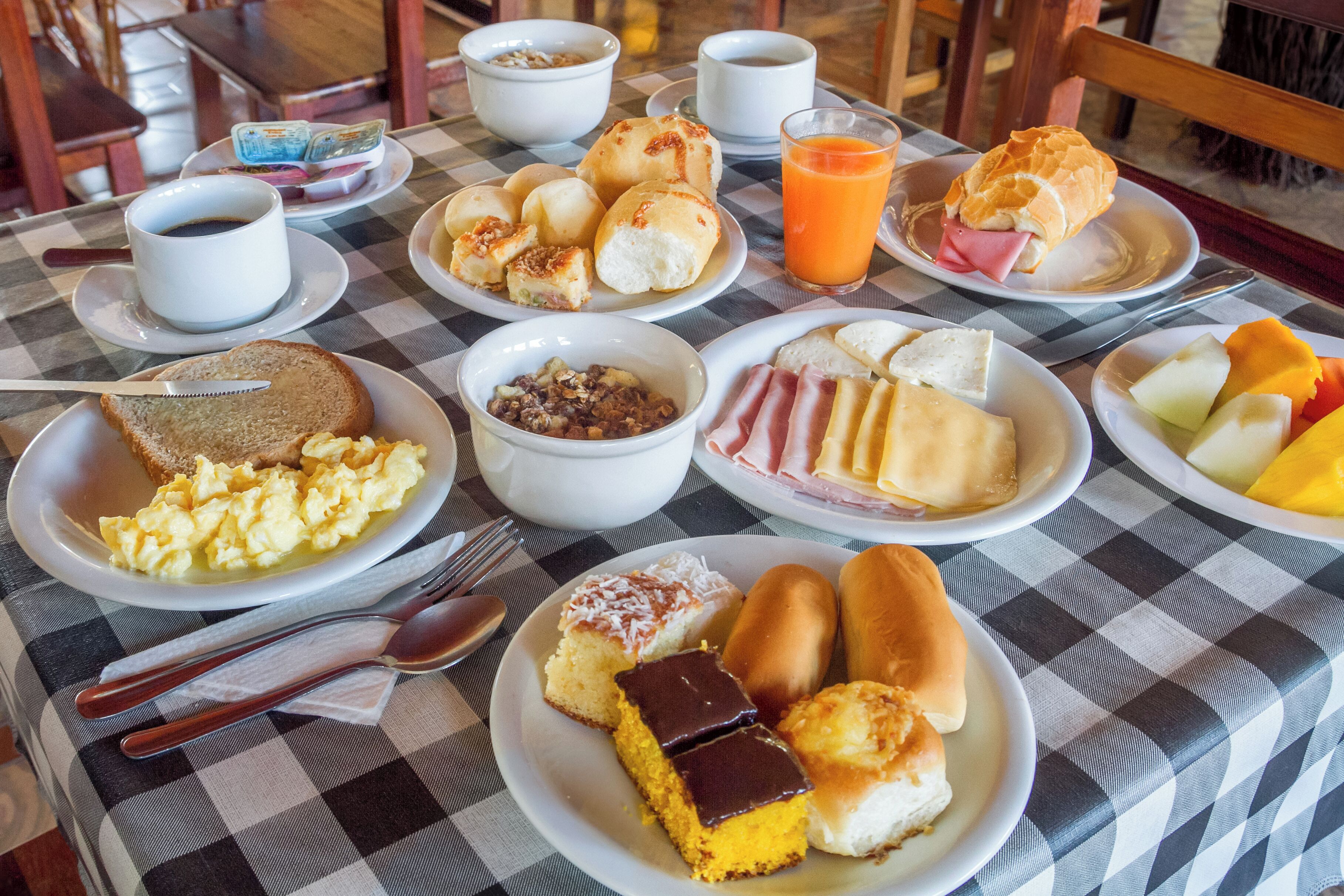 Un bufé de desayuno con diversos platos, incluyendo huevos, pan, bollería y fruta.