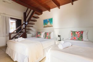 Quarto de hotel com duas camas, escada de madeira e um quadro na parede.