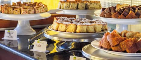 A display of various cakes on a counter with labels indicating names and prices.