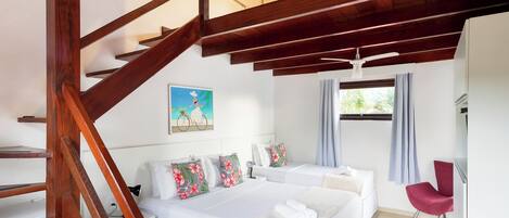 A hotel room with a wooden staircase, two beds, a red chair, and a window with curtains.