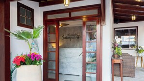 A hotel entrance with a large potted plant, a marble wall, and a wooden door. - Pousada Recanto do Jabaquara (Paraty)