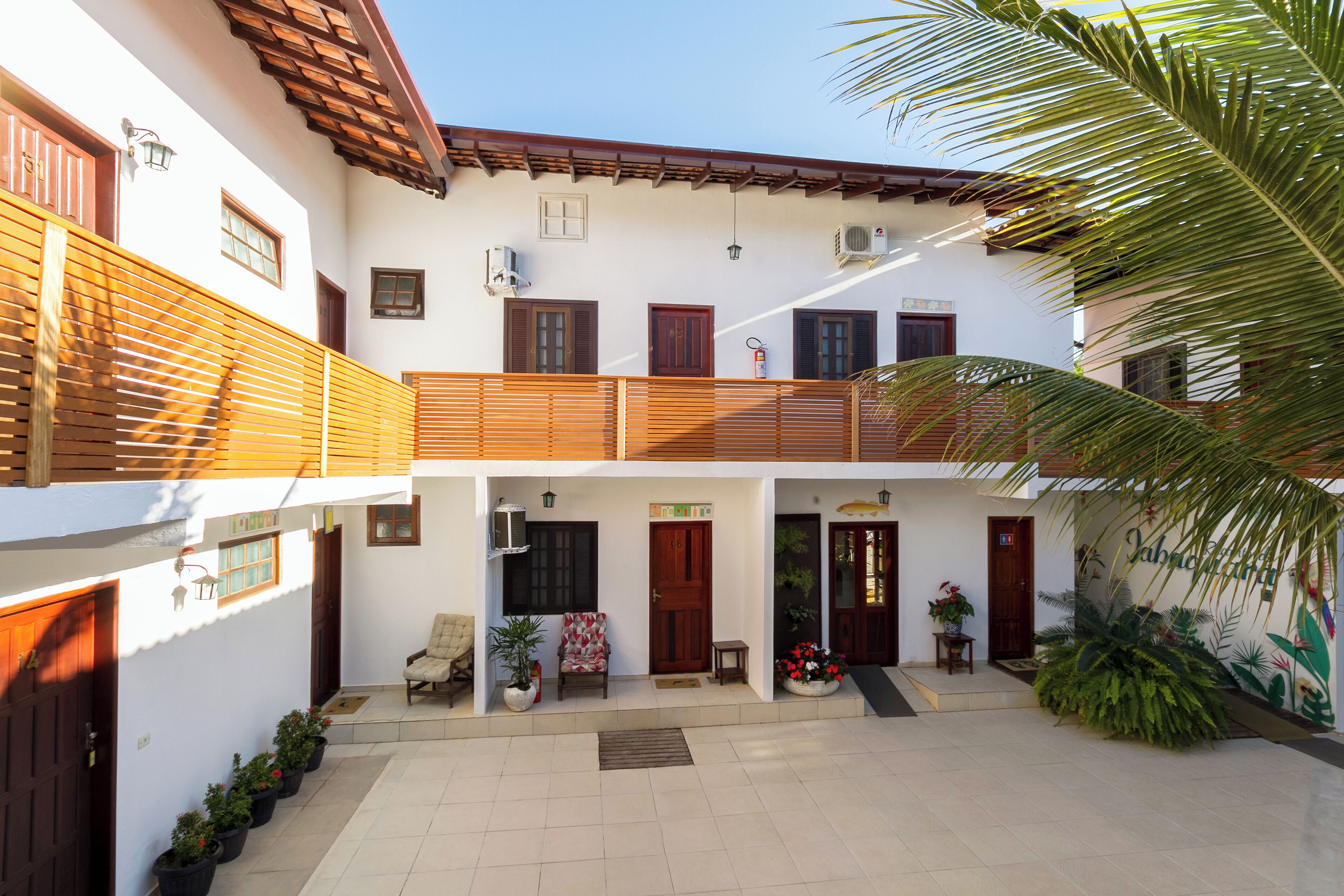 A courtyard with a wooden fence, potted plants, and a palm tree.