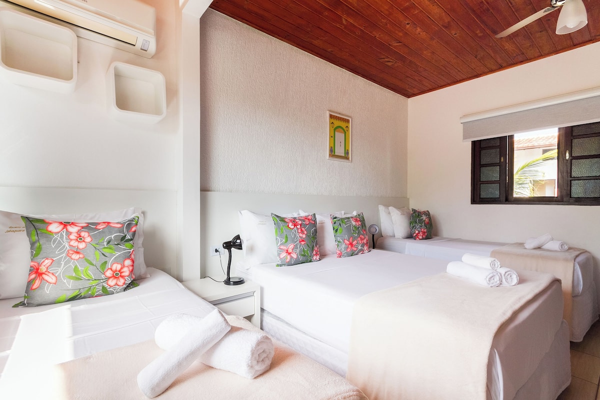 A hotel room with two beds, a desk with a lamp, and a window with a view.