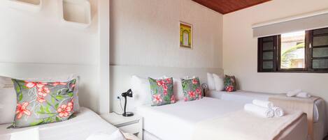 A hotel room with two beds, a desk with a lamp, and a window with a view.