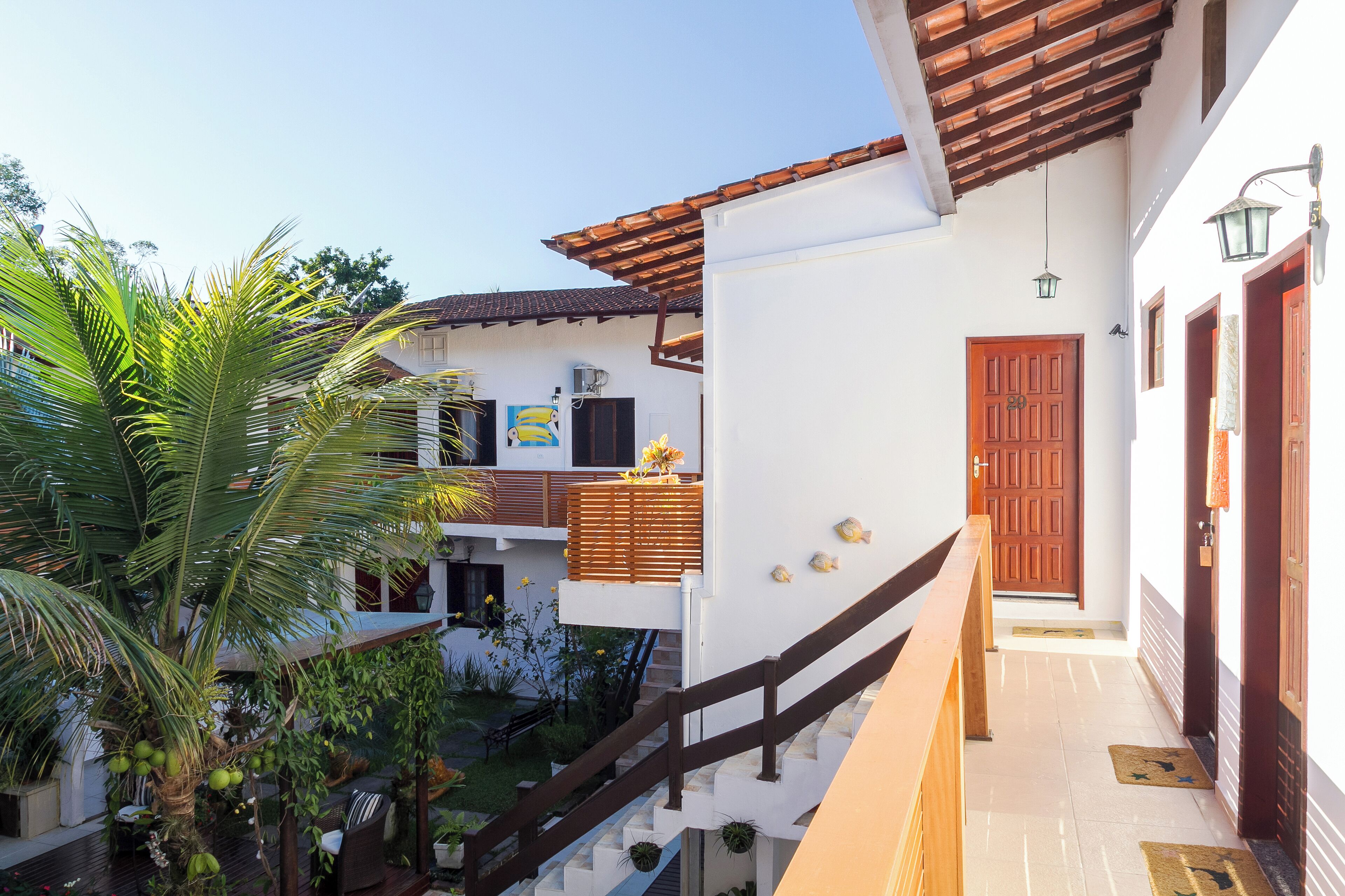 A modern building with a wooden staircase, a palm tree, and a door with a decorative design.