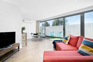 Una sala de estar moderna con un televisor de pantalla plana, un sofá rojo y un comedor con mesa y sillas.