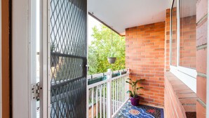 Un balcon avec une balustrade blanche, un pot de fleurs suspendu et un sol à motifs.