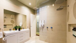 Uma casa de banho moderna com chuveiro envolto em vidro, toucador com espelho e banheira.