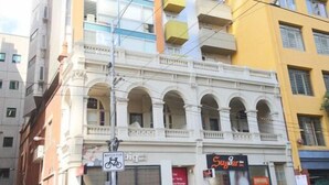 Un edificio de varios pisos con una tienda en la planta baja y un cartel de aparcamiento para bicicletas.